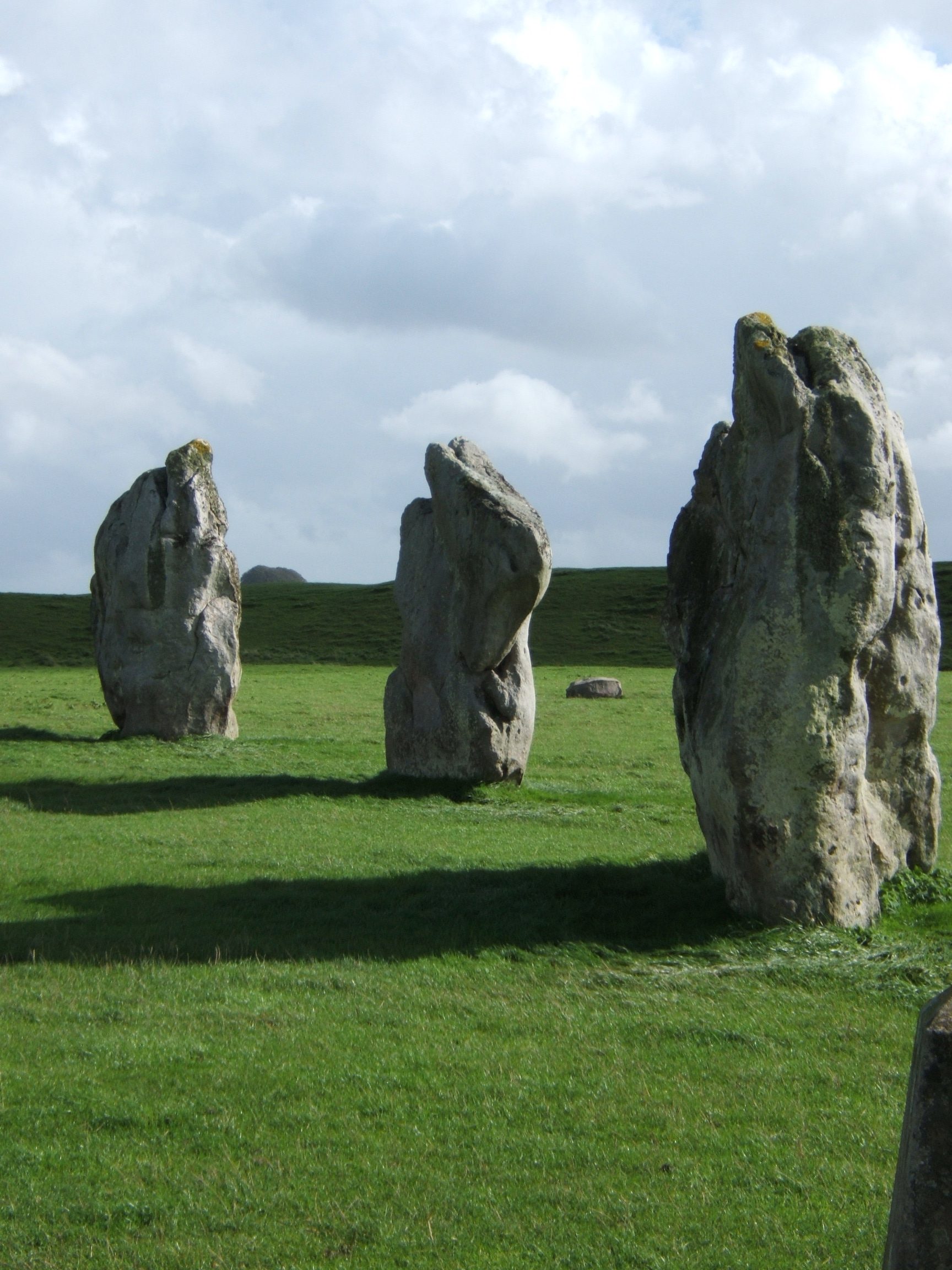 A line of tall Avebury stones beneath a clouded sky