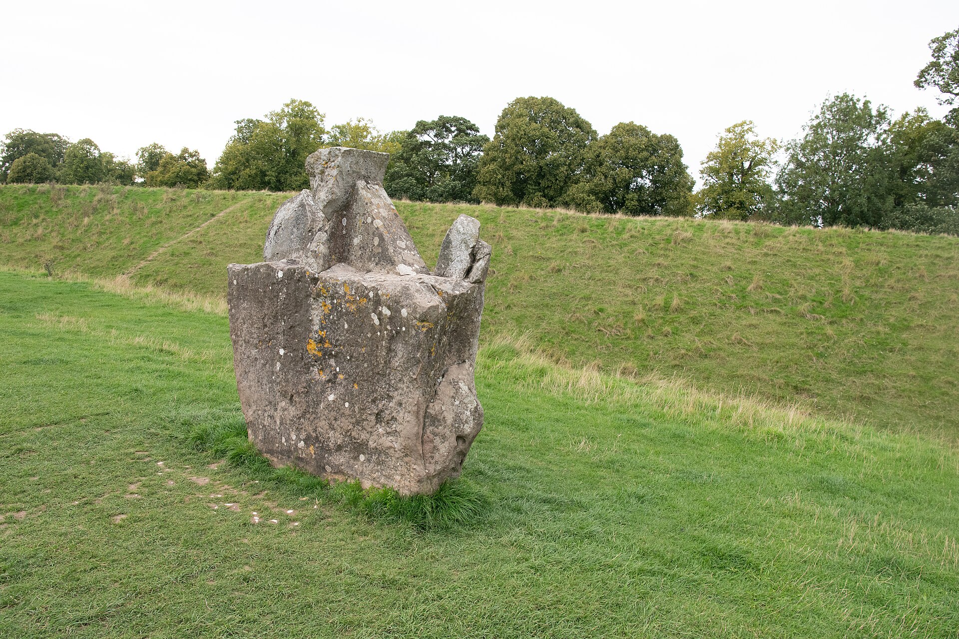 Large weathered sarsen stone beside Avebury’s grassy henge bank