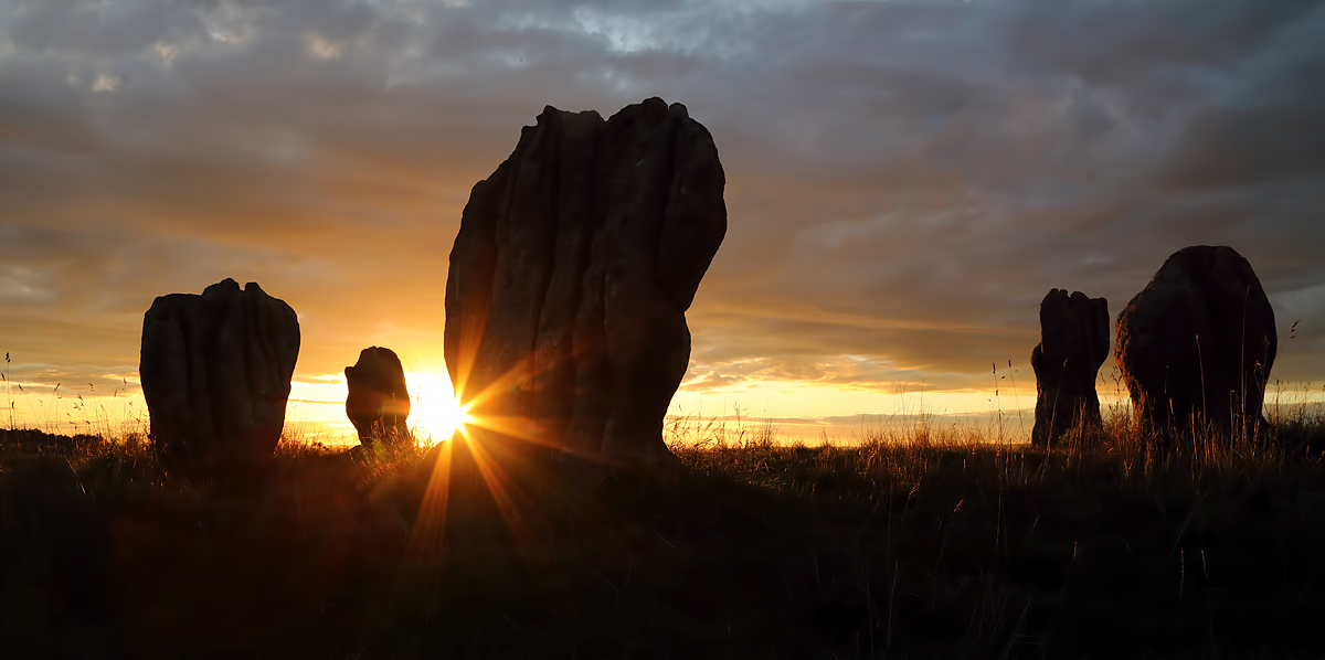 The grooved stones of Duddo silhouetted against a clouded sky